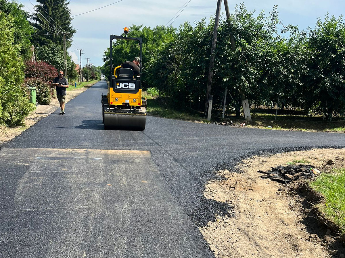 Falusi bekötőút aszfaltozása JCB hengerrel – friss kopóréteg fektetése